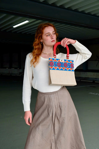 Cremeweiße/Beige Preloved (Secondhand) Handmade Handtasche im Vintage Stil von der Fair Trade Marke Aarong aus Bangladesch, die ländliche Kunsthandwerker unterstützt. Die Marke ist eine soziale Initiative der gemeinnützigen Organisation BRAC International. Die Tasche hat eine hübsche quadratische Form mit roten Henkeln und ist mit tollen Stickereien in Blau, Orange und Rot sowie kleinen schwarzen Pailletten verziert. Mit einem kleinen Innenfach, das mit einem Reißverschluss ausgestattet ist.