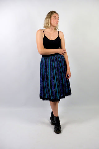 Hochwertiger 70s/80s High Waist Rock aus reiner Baumwolle im Folklore-/Landhaus-Stil, toller Schnitt in A-Linie mit stretchy Gummizugbund, Lochspitze am Saum sowie floralem Streifenmuster in Schwarz, Türkis, Lila, Flieder und Graugrün – ideal für eine L und ein absolutes Highlight