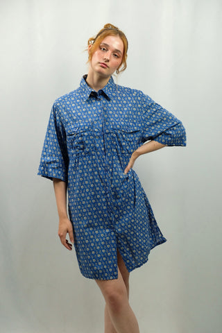 Blaue 90s Longbluse bzw. Blusenkleid aus reiner Baumwolle mit floralem Muster und Seitenschlitzen, die angegebene Größe ist 46, fällt aber eher kleiner aus – und wir empfehlen das Blusenkleid für einen lockeren/oversized Look einer M oder L