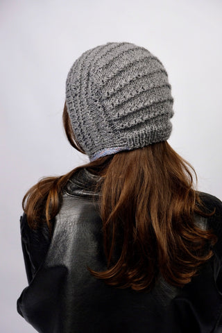 Handmade Bonnet aus Acryl-Garn in Grau mit bunten, schmalen Bindebändern.