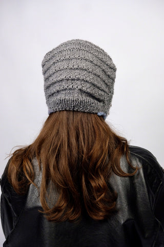 Handmade Bonnet aus Acryl-Garn in Grau mit bunten, schmalen Bindebändern.