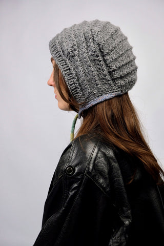 Handmade Bonnet aus Acryl-Garn in Grau mit bunten, schmalen Bindebändern.