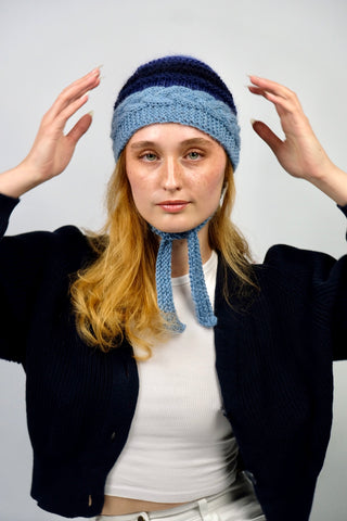 Handmade Bonnet aus Schurwolle- und Mohair-Mix Garn in Blautönen mit Zopfstrickmuster und Bindebändern.