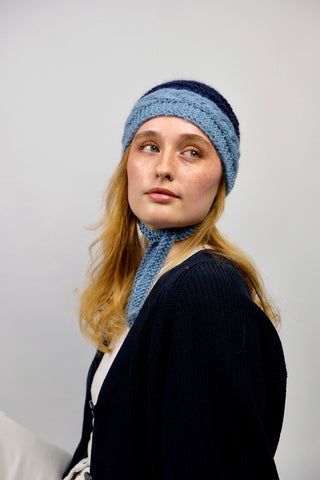 Handmade Bonnet aus Schurwolle- und Mohair-Mix Garn in Blautönen mit Zopfstrickmuster und Bindebändern.