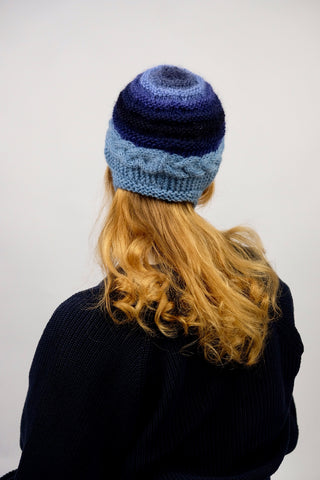 Handmade Bonnet aus Schurwolle- und Mohair-Mix Garn in Blautönen mit Zopfstrickmuster und Bindebändern.