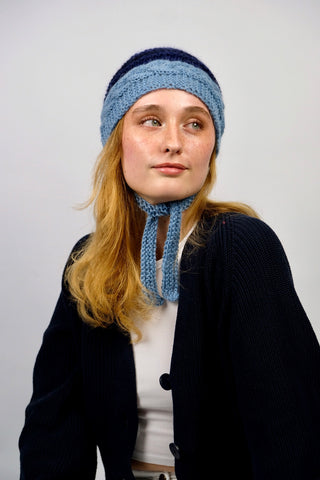 Handmade Bonnet aus Schurwolle- und Mohair-Mix Garn in Blautönen mit Zopfstrickmuster und Bindebändern.