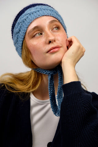 Handmade Bonnet aus Schurwolle- und Mohair-Mix Garn in Blautönen mit Zopfstrickmuster und Bindebändern.