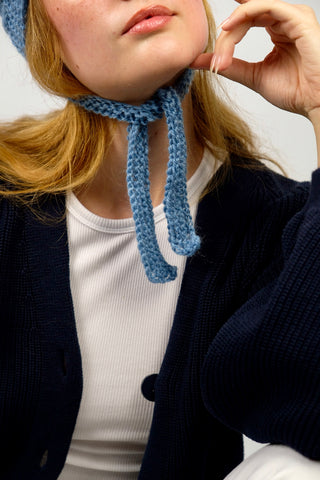 Handmade Bonnet aus Schurwolle- und Mohair-Mix Garn in Blautönen mit Zopfstrickmuster und Bindebändern.