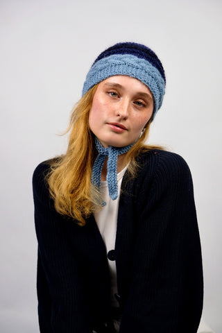 Handmade Bonnet aus Schurwolle- und Mohair-Mix Garn in Blautönen mit Zopfstrickmuster und Bindebändern.