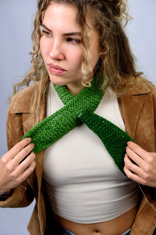 Handmade Minischal im Ascot-Stil aus weichem Acryl-Garn mit spitzen Enden sowie tollem Farbverlauf in Grüntönen. Wird durch eine kleine Öffnung auf einer Seite gesteckt, um ihn sicher am Hals zu halten.