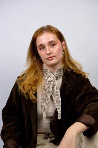 Handmade Minischal im Ascot-Stil aus Creme und Braun meliertem Bändchengarn mit Merino-Anteil. Wird durch eine kleine Öffnung auf einer Seite gesteckt, um ihn sicher am Hals zu halten.