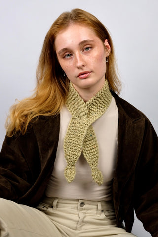 Handmade Minischal im Ascot-Stil aus pistaziengrünem, leicht meliertem Tweed-Garn mit Blatt-Details an den Enden. Wird durch eine kleine Öffnung auf einer Seite gesteckt, um ihn sicher am Hals zu halten.