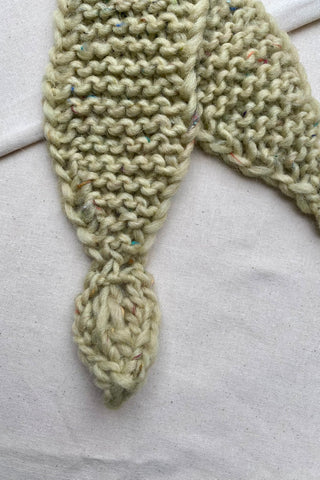 Handmade Minischal im Ascot-Stil aus pistaziengrünem, leicht meliertem Tweed-Garn mit Blatt-Details an den Enden. Wird durch eine kleine Öffnung auf einer Seite gesteckt, um ihn sicher am Hals zu halten.