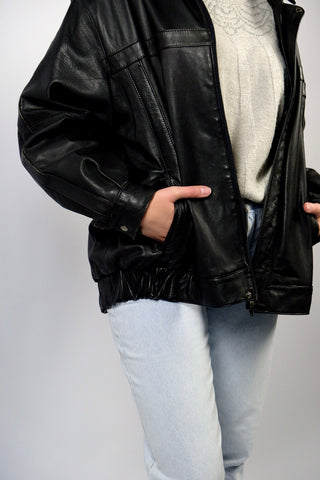 Schwarze 90s Bomberjacke aus echtem Glattleder mit Reißverschluss, Druckknöpfen und seitlichen Eingrifftaschen; toll erhalten und unisex tragbar – wir empfehlen die Jacke einer heutigen XL und ausschließlich für große Körpergrößen (bitte Maße beachten) – ein absolutes Highlight