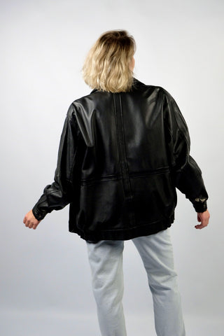 Schwarze 90s Bomberjacke aus echtem Glattleder mit Reißverschluss, Druckknöpfen und seitlichen Eingrifftaschen; toll erhalten und unisex tragbar – wir empfehlen die Jacke einer heutigen XL und ausschließlich für große Körpergrößen (bitte Maße beachten) – ein absolutes Highlight
