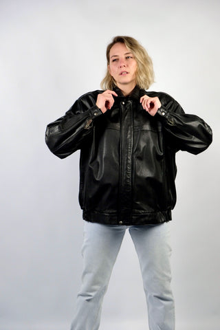 Schwarze 90s Bomberjacke aus echtem Glattleder mit Reißverschluss, Druckknöpfen und seitlichen Eingrifftaschen; toll erhalten und unisex tragbar – wir empfehlen die Jacke einer heutigen XL und ausschließlich für große Körpergrößen (bitte Maße beachten) – ein absolutes Highlight