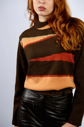 Dunkelbrauner 90s Pullover mit Stehkragen und tollem Grafikmuster in Orange, Rot, Beige und Gold – die angegebene Größe ist L, für einen lockeren Look empfehlen wir den Pullover jedoch eher einer heutigen M oder der Zwischengröße S/M