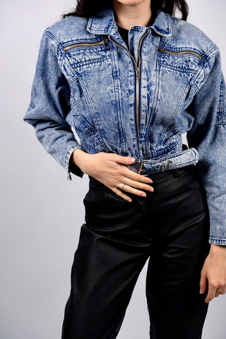 Atemberaubende 80s Acid Wash Jeansjacke aus reiner Baumwolle in kurzem Bomber-/Biker-Schnitt mit Gürtel und Schnürung am Rücken – die Jacke hat leichte Schulterpolster, welche zum authentischen 80s Design dazugehören, aber je nach Belieben auch herausgetrennt werden könnten – ideal für eine XS bis S, ein seltenes Fundstück und absolutes Highlight