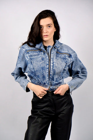 Atemberaubende 80s Acid Wash Jeansjacke aus reiner Baumwolle in kurzem Bomber-/Biker-Schnitt mit Gürtel und Schnürung am Rücken – die Jacke hat leichte Schulterpolster, welche zum authentischen 80s Design dazugehören, aber je nach Belieben auch herausgetrennt werden könnten – ideal für eine XS bis S, ein seltenes Fundstück und absolutes Highlight