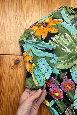 80s T-Shirt mit Rundhalsausschnitt, Knopfleiste vorn und tollem Botanical Crazy Pattern Print in Schwarz, Türkis, (Oliv)grün, Gelb, Orange, Pink und Weiß – wir empfehlen das Shirt einer M bis L
