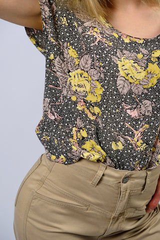Locker, kurz und boxy geschnittenes 80s Viskose Shirt mit weitem Rundhalskragen, Knopfleiste am Rücken und tollem Blumenmuster in Schwarz, Weiß, Graubraun, Rosa und gedeckten Gelbtönen – wir empfehlen das Shirt einer S bis M