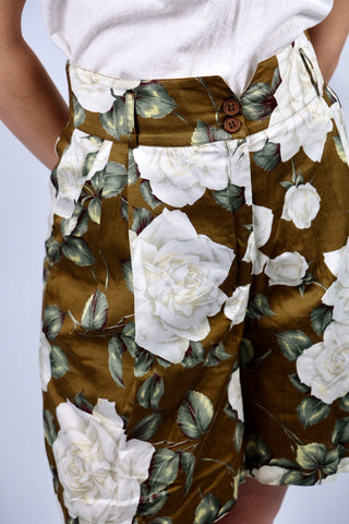 Traumhafte 80s Shorts made in Italy aus Seide (vermutlich handelt es sich um eine hochwertige Duchesse- oder Shantung-/Wildseide) – die Shorts hat einen edlen, matten Glanz und ein florales Muster in tollen Farben (Braun, Weiß, Creme, Greige, Salbei, Hellgrün und Weinrot) sowie klassischen Ultra High Waist Schnitt mit zwei Knöpfen, Bundfalten und seitlichen Eingrifftaschen – ein Signature-Design der gehobenen 80s-Mode, ein seltenes Fundstück und absolutes Highlight in hervorragendem Zustand.