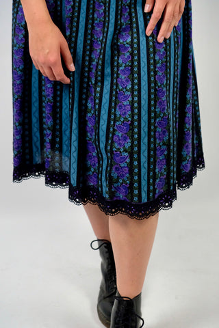 Hochwertiger 70s/80s High Waist Rock aus reiner Baumwolle im Folklore-/Landhaus-Stil, toller Schnitt in A-Linie mit stretchy Gummizugbund, Lochspitze am Saum sowie floralem Streifenmuster in Schwarz, Türkis, Lila, Flieder und Graugrün – ideal für eine L und ein absolutes Highlight