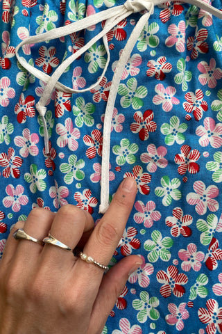 Ärmelloses, blaues 70s Baumwollkleid in A-Linie mit Taillenband und Blümchenmuster in Hellgrün, Blau, Rot, Rosa und Weiß – durch die Schleife am Ausschnitt noch etwas anpassbar, zu empfehlen für eine XS – ein absolutes Highlight