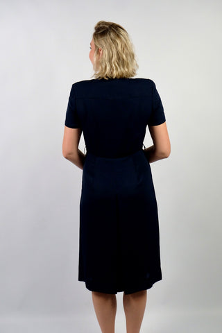 Elegantes, dunkelblaues 80s/90s Kleid made in Italy mit durchgehender Knopfleiste, leichten Schulterpolstern (welche je nach Belieben auch einfach herausgetrennt werden könnten) und Beinschlitzen – die angegebene Größe ist L, fällt unserer Einschätzung nach etwas kleiner aus: wir empfehlen das Kleid einer heutigen M oder der Zwischengröße M/L