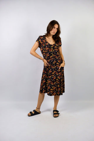 dunkelblaues 80s/90s Viskose Kleid in lockerem Schnitt mit aufgesetzten Taschen, leichten Schulterpolstern (welche je nach Belieben auch einfach herausgetrennt werden könnten) sowie Blümchenmuster in Gelb, Rot, Orange, Weiß und Grüntönen – wir empfehlen das Kleid einer S/M oder kleinen M je nach gewünschter Passform