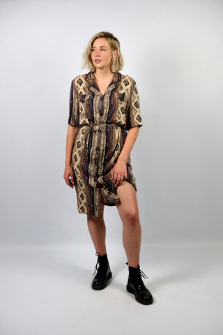 Locker und gerade geschnittenes 90s Blusenkleid made in Italy aus reiner Viskose mit durchgehender Knopfleiste, Bindegürtel für die Taille und Boho Print in Brauntönen, Beige, Schwarz, Weiß und Blau – wir empfehlen das Kleid einer heutigen L