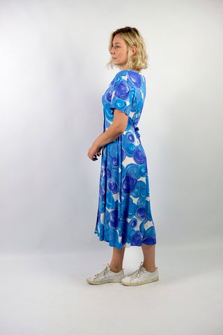 80s/90s Midikleid aus reiner Viskose mit V-Ausschnitt, durchgehender Knopfleiste, Bändchen zum Binden am Rücken und Crazy Pattern Print in Blau, Lilablau, Türkis und Weiß – wir empfehlen das Kleid einer heutigen L