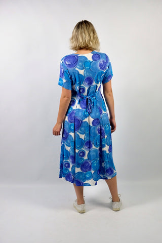 80s/90s Midikleid aus reiner Viskose mit V-Ausschnitt, durchgehender Knopfleiste, Bändchen zum Binden am Rücken und Crazy Pattern Print in Blau, Lilablau, Türkis und Weiß – wir empfehlen das Kleid einer heutigen L