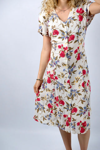Cremeweißes/meliertes 80s/90s Kleid mit durchgehender Knopfleiste, Bändchen zum Binden am Rücken, Beinschlitzen und tollem Blumenmuster in Rot, Blau, Gelb und Grünbraun – es sind leichte Schulterpolster vorhanden, welche je nach Belieben aber auch ganz einfach herausgetrennt werden könnten – ideal für eine heutige S bis M und ein absolutes Highlight