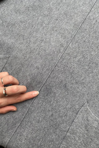 Grau meliertes Preloved (Secondhand) Herbstkleid aus einer Boutique, weicher Strickstoff und lässiger Schnitt mit aufgesetzten Taschen und Fransen – tragbar von einer S bis M