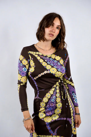 Dunkelbraunes 70s Boho Langarmkleid in figurbetontem Schnitt mit Bindegürtel und tollem floralem Print in Gelb, Flieder, Lila, (Creme)weiß, Orange und Blau – insgesamt leicht elastisch, tragbar von einer XS bis S je nach gewünschter Passform und ein absolutes Highlight