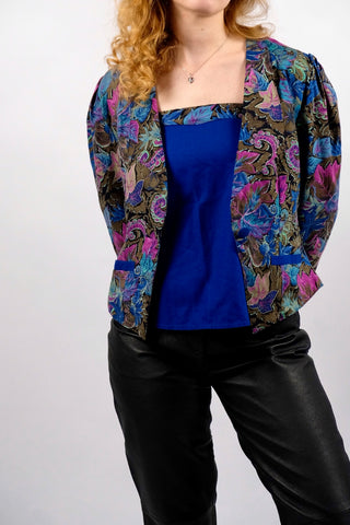 80s Zweiteiler bestehend aus einem Blazer mit abstrakt-floralem Crazy Pattern Print in Blautönen, Braun, Schwarz, Pink und Mint sowie dazu passendem Trägertop in Royalblau, ebenfalls dezent am Ausschnitt gemustert – das Set besteht aus angenehmer Materialmischung (Baumwolle-Modal) und ist für eine heutige XS bis S zu empfehlen (bitte Anmerkung beachten)