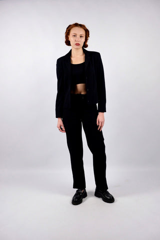 Atemberaubender 90s/00s Hosenanzug aus schwarzer Viskose und Schurwolle; das Set besteht aus einem taillierten, klassischen Blazer sowie einer dazu passenden Mid Waist Hose mit geradem Bein – außerdem hat der Zweiteiler dezente, geschnürte Kunstleder-Details – ein seltenes Fundstück und absolutes Highlight in Größe S