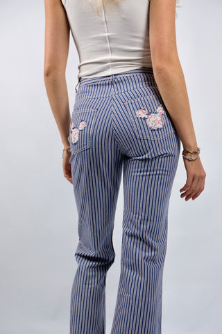 Blau-Weiß gestreifte 90s Hose aus reiner Baumwolle mit Mid Waist Bundhöhe und unten leicht ausgestelltem Bein sowie floralem Mickey Mouse Design auf den hinteren Hosentaschen – ein absolutes Highlight und passend für eine heutige XXS