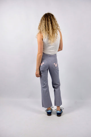 Blau-Weiß gestreifte 90s Hose aus reiner Baumwolle mit Mid Waist Bundhöhe und unten leicht ausgestelltem Bein sowie floralem Mickey Mouse Design auf den hinteren Hosentaschen – ein absolutes Highlight und passend für eine heutige XXS