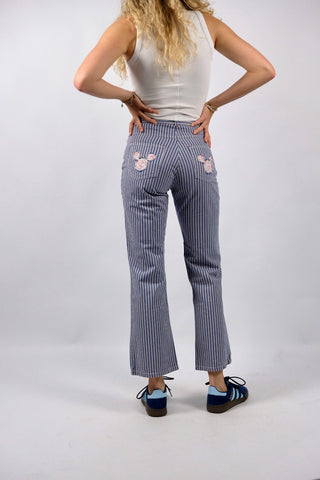 Blau-Weiß gestreifte 90s Hose aus reiner Baumwolle mit Mid Waist Bundhöhe und unten leicht ausgestelltem Bein sowie floralem Mickey Mouse Design auf den hinteren Hosentaschen – ein absolutes Highlight und passend für eine heutige XXS