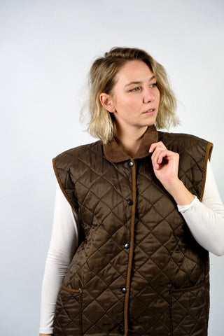 Braune 90s Steppweste made in England, mit Cordkragen und Taschen, die angegebene Größe ist L, fällt unserer Einschätzung nach jedoch größer aus (ca. XL, bitte Maße beachten)
