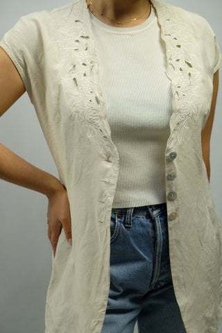 Cremeweiße 90s Bluse aus sehr hochwertigem Materialmix mit tollem Design am Kragen und Schnürung am Rücken, die angegebene Größe ist M, wir empfehlen die Bluse eher einer S – ein absolutes Highlight