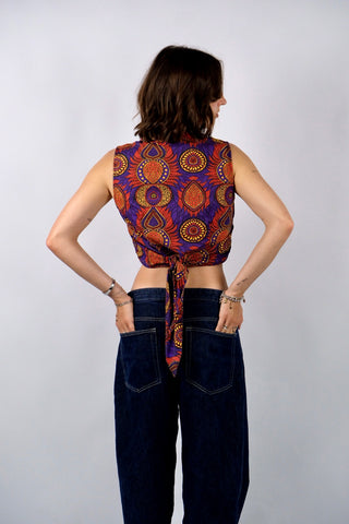 Ärmellose Y2k Baumwollbluse in bauchfreiem Schnitt zum Binden – kann entweder vorne oder hinten geknotet werden – mit tollem Boho Print in Lila, Orangerot, Gelb und Schwarz. Die angegebene Größe ist S, fällt eher klein aus: wir empfehlen die Bluse einer XS oder der Zwischengröße XS/S – ein absolutes Highlight