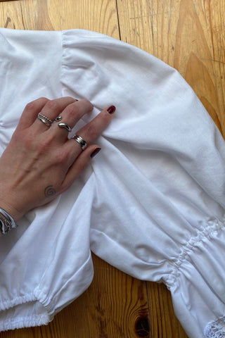 Traumhafte weiße 80s Folklore Dirndlbluse in typisch verkürztem Schnitt mit Gummizugsaum, tollen Puffärmeln und Details aus Lochspitze – made in Germany/Bavaria und ca. tragbar von einer XS bis S je nach gewünschter Passform (bitte Maße beachten) – ein absolutes Highlight