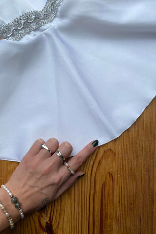 Weiße 70s Bluse mit Stehkragen, Trompetenärmeln und silbernen Verzierungen, wird am Rücken mit einer Knopfleiste geschlossen – wir empfehlen die Bluse einer heutigen S bis M – ein seltenes Fundstück und absolutes Highlight