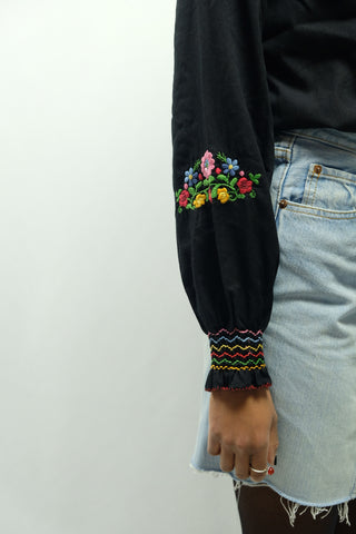 Schwarze, eher kurz geschnittene 90s Bluse im 70er-Boho-Stil mit tollen floralen Stickereien und leichten Ballonärmeln – ein absolutes Highlight