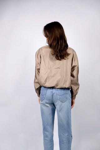 80s Bluse in tollem Bomber-/Blouson-Schnitt mit Stehkragen und Schulterpolstern (welche bei Bedarf auch herausgetrennt werden könnten); die Farbe würden wir als Oliv-Gold bezeichnen, die angegebene Größe ist L – tragbar von M bis L