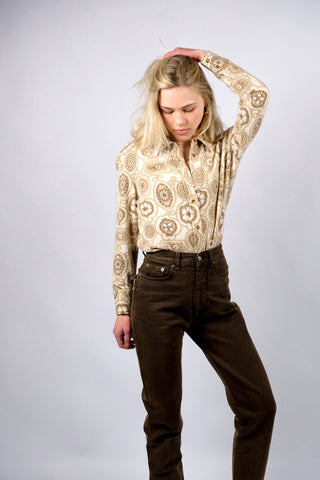 Cremefarbene 70s Bluse mit tollem Boho-Blumenmuster in Beige und Braun, die Größe entspricht ca. einer heutigen M bei einer für die 70s typischen figurbetonten/engen Passform – für einen eher lockeren Look empfehlen wir die Bluse aber einer XS oder S – bitte Maße beachten