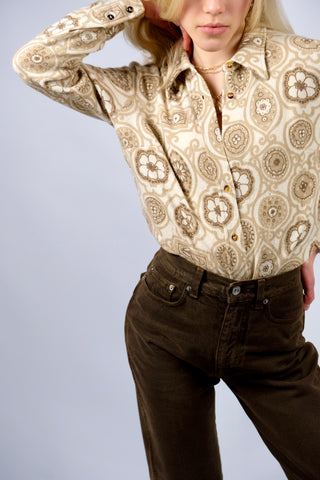 Cremefarbene 70s Bluse mit tollem Boho-Blumenmuster in Beige und Braun, die Größe entspricht ca. einer heutigen M bei einer für die 70s typischen figurbetonten/engen Passform – für einen eher lockeren Look empfehlen wir die Bluse aber einer XS oder S – bitte Maße beachten